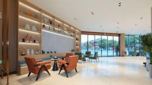 A spacious lobby with a large seating area, a bookshelf filled with decorative items, and a view of the outside through large windows. - Tongren Grand Hotel (Tongren High-speed Railway Station Ancient City Pedestrian Street Branch) (Tongren)