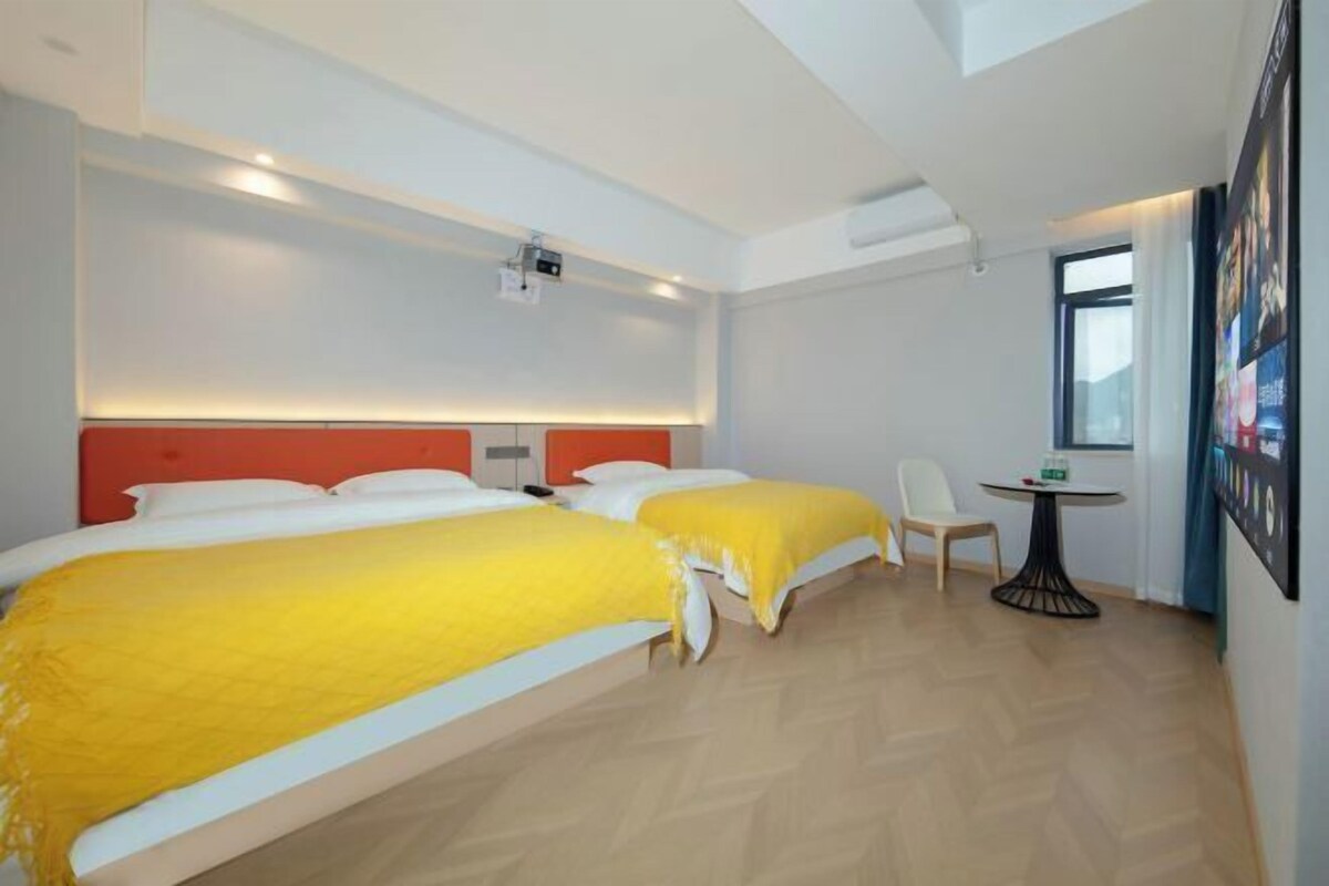 Una habitación de hotel con dos camas, una mesita y una silla.