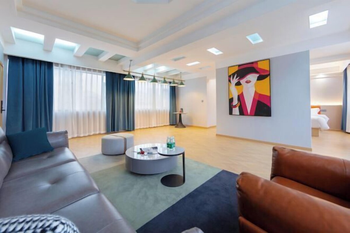 Una sala de estar moderna con sofá, reposapiés, una mesa de centro y una obra de arte en la pared.