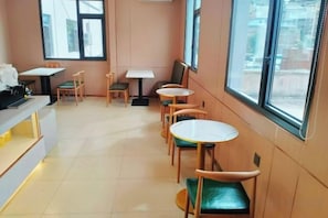 Um café com mesas e cadeiras dispostas para os clientes.