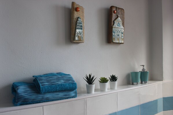 Une salle de bain avec une serviette, des plantes en pot et un distributeur de savon.