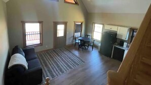 A spacious living area with a high ceiling, a dining table, and a kitchen area.