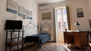 A bedroom with a bed, a desk, a chair, a TV, and artwork on the walls. - Casa Negli Iblei - South East Sicily (Canicattini Bagni)
