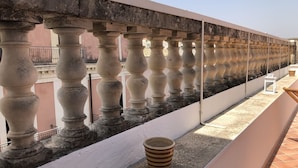 A balcony with stone balustrades, a tiled floor, and a potted plant. - Casa Negli Iblei - South East Sicily (Canicattini Bagni)