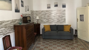A living room with a sofa, a wooden cabinet, a radio, and a patterned floor. - Casa Negli Iblei - South East Sicily (Canicattini Bagni)