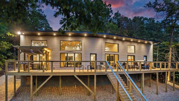 A modern house with a deck, large windows, and a staircase.