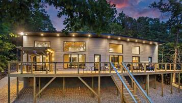 A modern house with a deck, large windows, and a staircase.