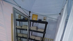 Une pièce avec une armoire à portes miroir, une étagère avec des serviettes pliées, un tapis à motifs et une poubelle blanche.