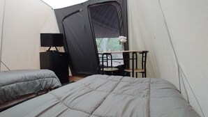 Une tente équipée d’un lit, d’une petite table et d’une chaise.