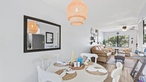 Un coin repas avec une table ronde, des chaises blanches et un luminaire suspendu en rotin.
