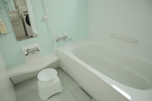 Et badeværelse med badekar, toilet og håndvask.