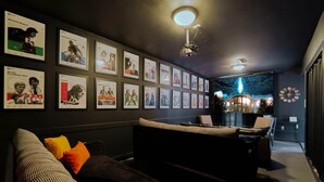 Una sala moderna con una paleta de colores oscuros, un sofá, una mesa de centro y una pared decorada con cuadros enmarcados.