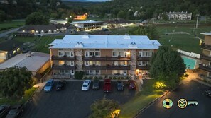 A multi-story hotel with a parking lot and a swimming pool.
