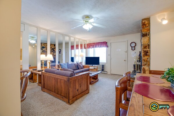 A living room with a wooden sofa, a TV, and a stone accent wall.