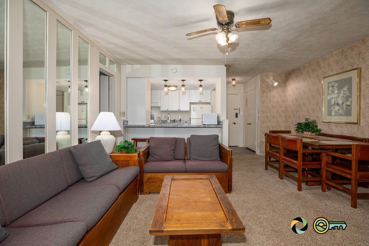 Una sala moderna con sofá, mesa de centro y comedor con muebles de madera.