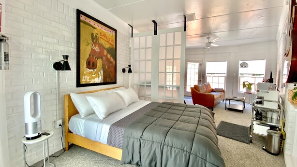 Een moderne slaapkamer met een bed, een schilderij, een bureau en een stoel.