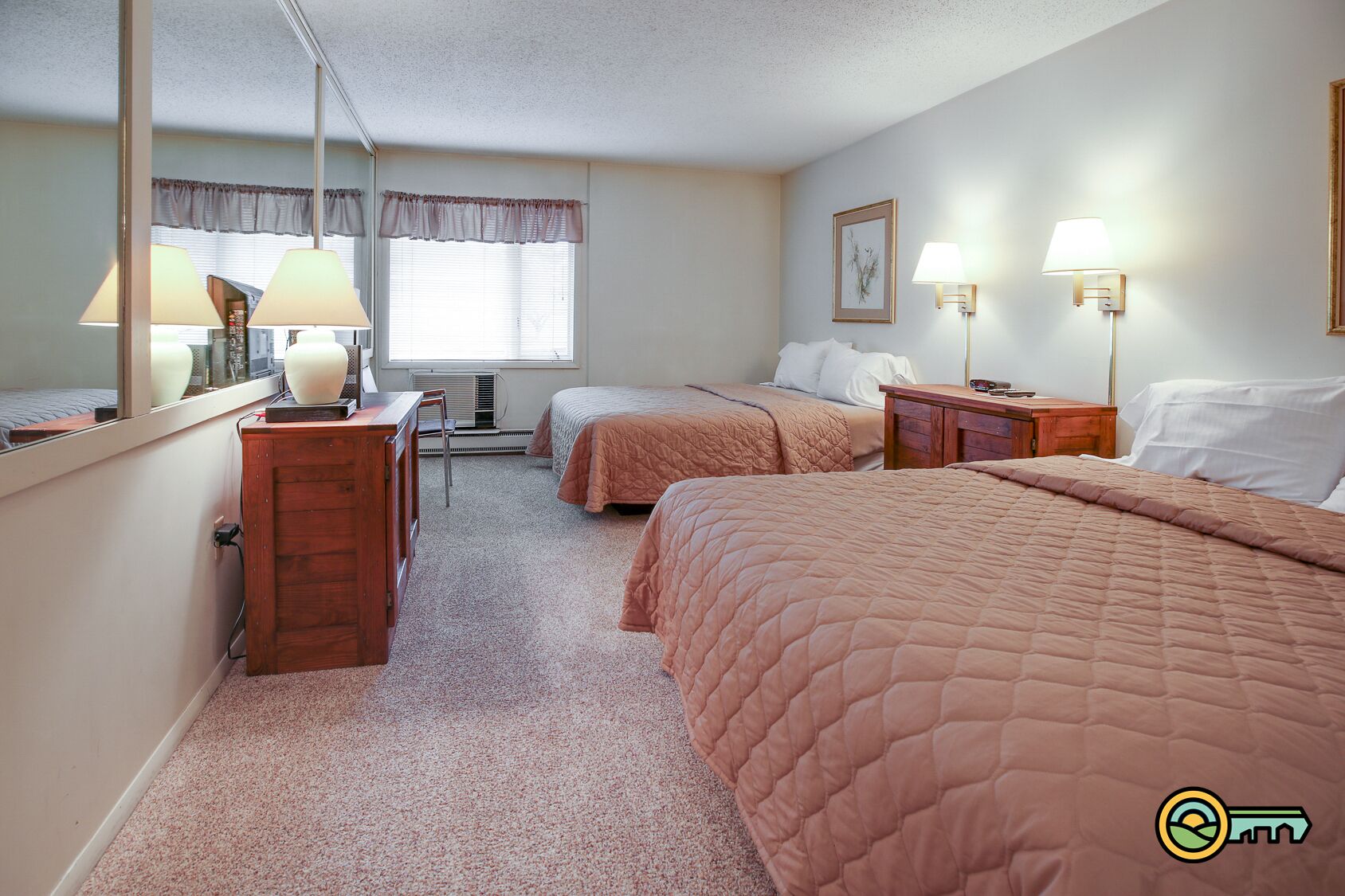 A bedroom with two beds, a desk, a chair, and a window with curtains.