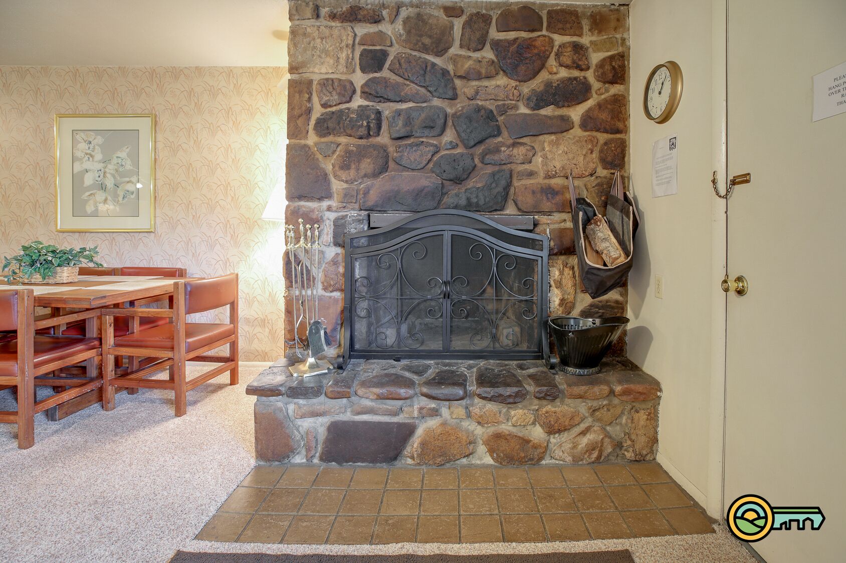 A stone fireplace with a metal door, a clock, and a door with a chain lock.