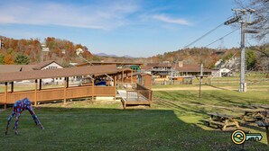 A wooden structure with a covered seating area, a picnic table, and a playground. - Ski/MTB/Golf Condo (#117) - Slope side | Ski slope & Resort views | Walk-in access! (Basye)