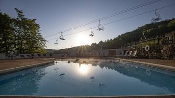 A swimming pool with lounge chairs and a stone wall.