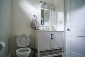 Bathroom features a toilet, sink, and cabinet, with a towel rack and door.