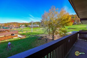 Blick von einem Balkon auf einen Park mit Picknicktischen, einem Spielplatz und einem Gebäude mit Gründach.