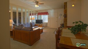 Ein Wohnzimmer mit Sofa, Fernseher und Esstisch mit Platzsets.