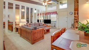 A spacious living room with a wooden sofa, a television, and a dining area with a table and chairs. - Ski/MTB/Golf Condo (#131) - Slope side | Slope & Resort valley views | Vaulted ceilings! (Basye)