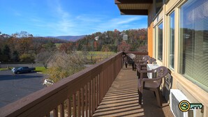 A balcony with a view of a parking lot and autumn trees, wooden railing, and outdoor furniture. - Ski/MTB/Golf Condo (#132) - Slope side | Mountain, golf course views | Vaulted ceilings! (Basye)