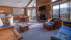 A spacious living area with a fireplace, wooden furniture, and large windows offering a view of the outdoors.