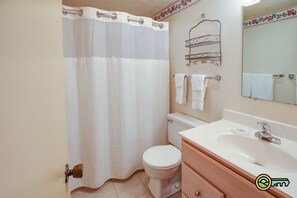 Un baño con inodoro, lavamanos y cortina de ducha.