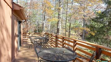 Une terrasse extérieure avec des rampes en bois, des tables et des chaises en métal.