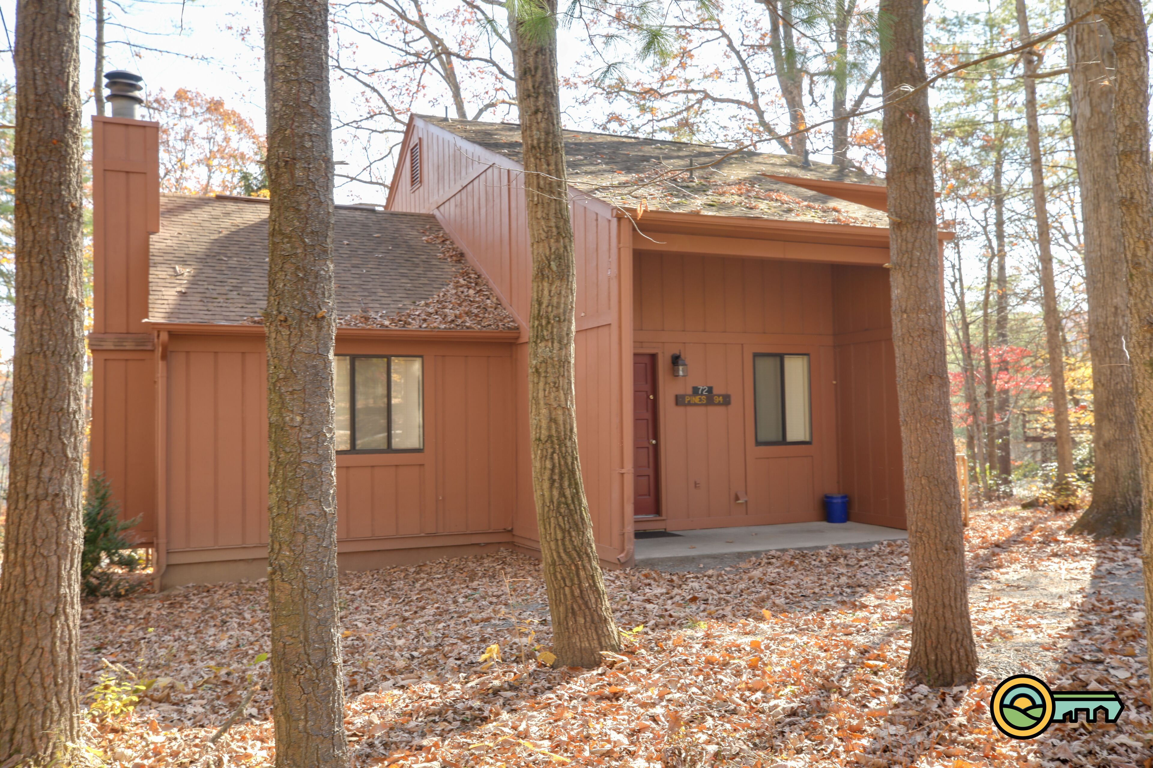 Une cabane en bois avec une cheminée, une porte avec une enseigne et une fenêtre.
