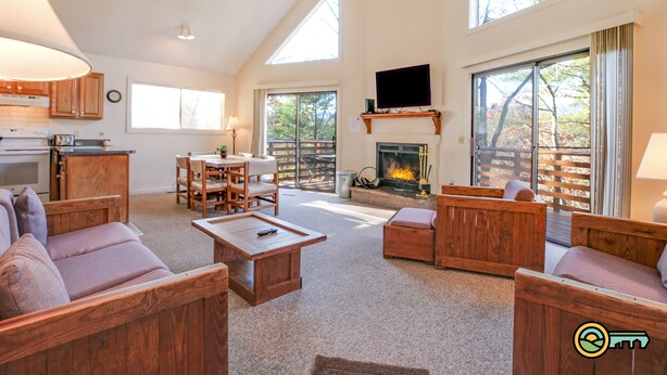 A spacious living room with wooden furniture, a fireplace, and large windows offering views of the outdoors. - Cozy Mountain Chalet (#102) - Quiet location | Summertime secluded | Great winter views! (Basye)