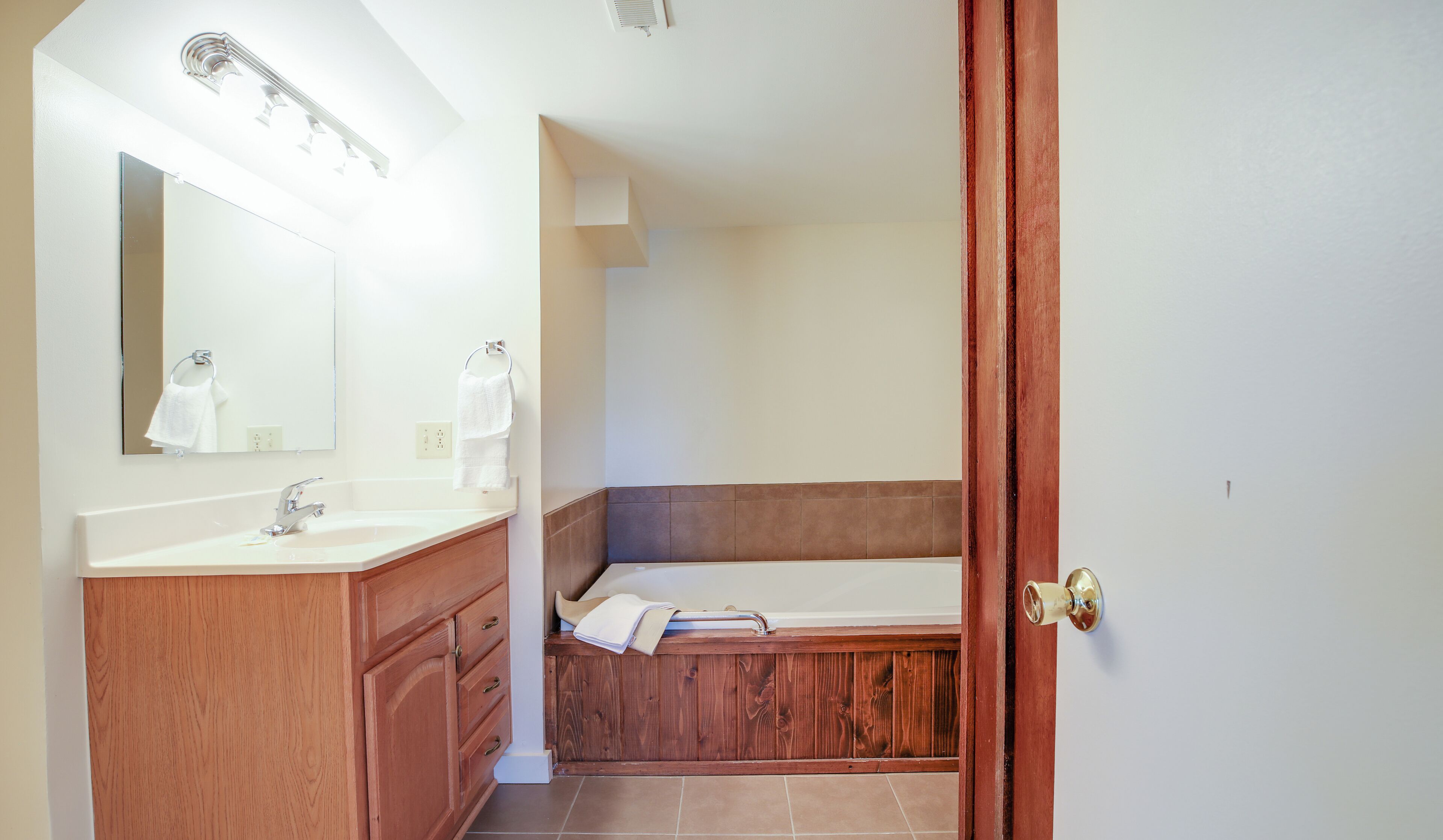 Une salle de bain avec un meuble-lavabo en bois, un évier, un miroir et une baignoire.