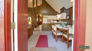 A kitchen with wooden cabinets, a dining area with a table and chairs, and a red carpet leading to the door. - Golf-lover's Mountain Chalet (#150A) - Great view of golf course! (Basye)