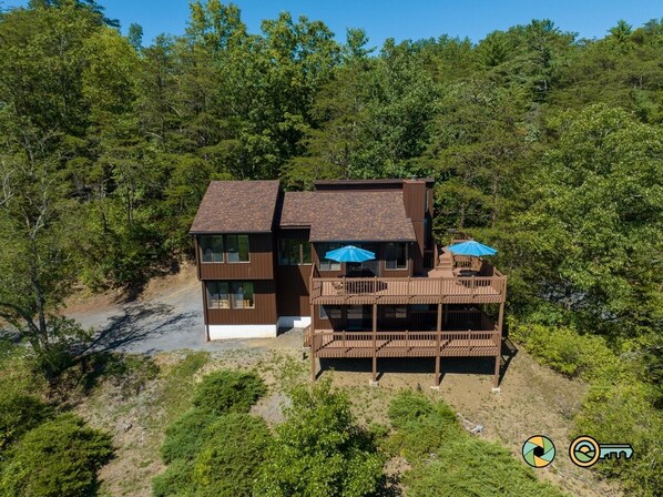 A two-story house with a wooden deck and a blue umbrella.