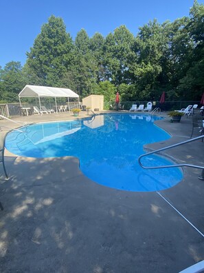 A swimming pool with a white canopy and lounge chairs.