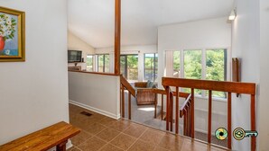 Un interior espacioso con una escalera de madera, ventanas amplias y vistas al exterior.