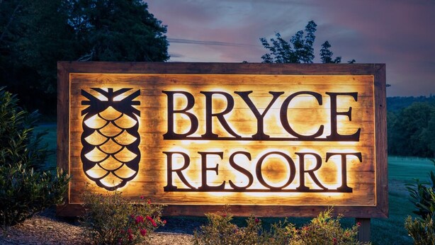 A wooden sign for Bryce Resort with a pineapple design.