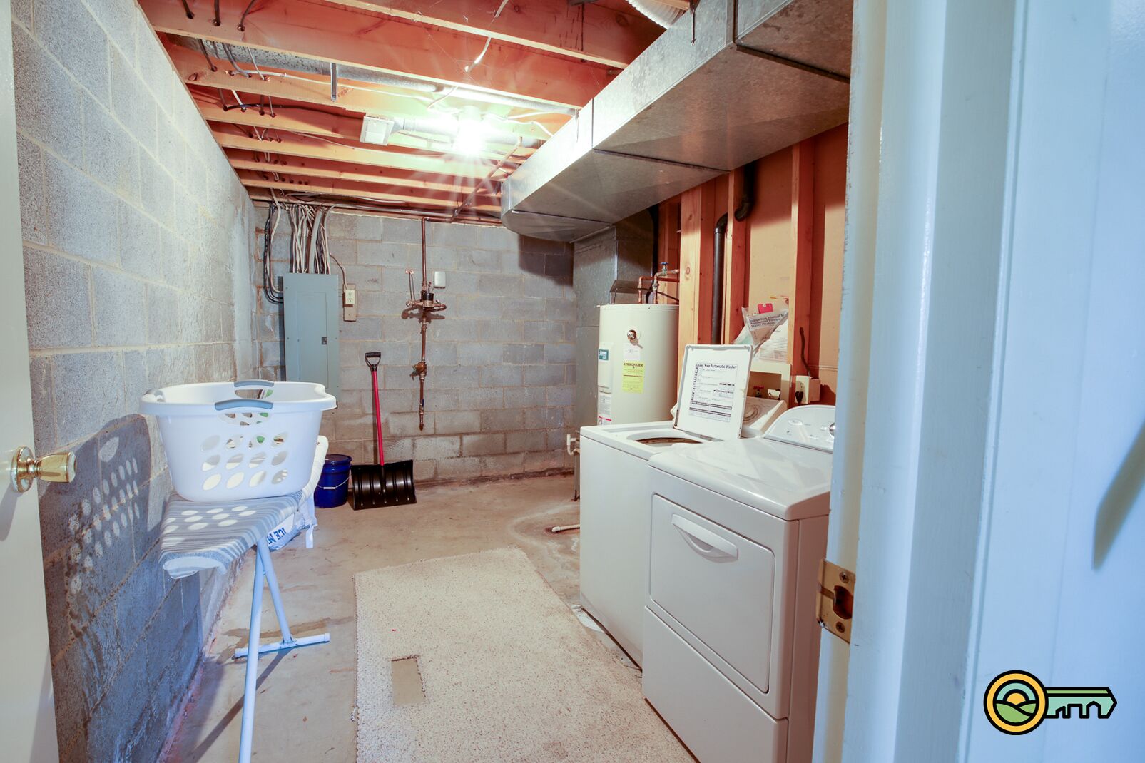 A laundry room with a washing machine, a dryer, a water heater, and a utility sink.