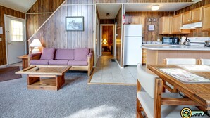 A cozy interior with a wooden staircase, a sofa, a dining table, and a kitchen area.