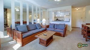 Ein modernes Wohnzimmer mit einer Eckcouch, einem Holztisch und einem Deckenventilator.