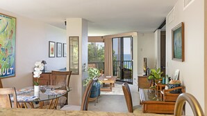 Un vaste espace dédié à la salle à manger, avec une table en verre, des chaises en bois et une vue sur l’extérieur.