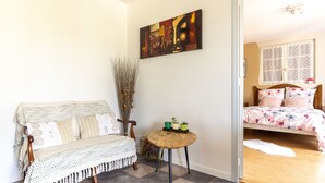 A cozy room with a wooden bench, a small round table with plants, and a bed with floral bedding. - Dorlanne - One Bedroom House, Sleeps 2 (Saint-Palais)