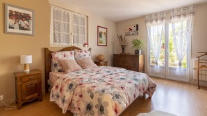 A bedroom with a floral bedspread, wooden nightstands, a dresser, and a window with curtains. - Dorlanne - One Bedroom House, Sleeps 2 (Saint-Palais)