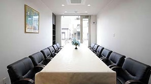 Une salle de conférence avec une longue table et des fauteuils en cuir noir.