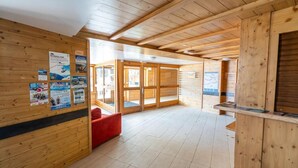 A wooden interior with a red sofa, wooden walls, and a tiled floor. - 150m from resort center, 2nd floor, swimming pool, sauna, terrace, ski locker, 33m², Les Orres (Les Orres)