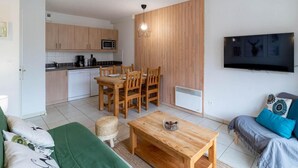 A compact living space with a kitchenette, dining area, and a TV mounted on the wall. - 150m from resort center, 2nd floor, swimming pool, sauna, terrace, ski locker, 33m², Les Orres (Les Orres)