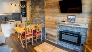 A modern kitchen with a stone wall and a fireplace. - 150m from ski slopes, 7th floor, view terrace, swimming pool, sauna, terrace, balcony, ski locker (Les Orres)